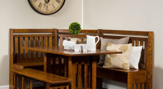 Corner dining bench set with wooden table and pillows in a dining room setting.